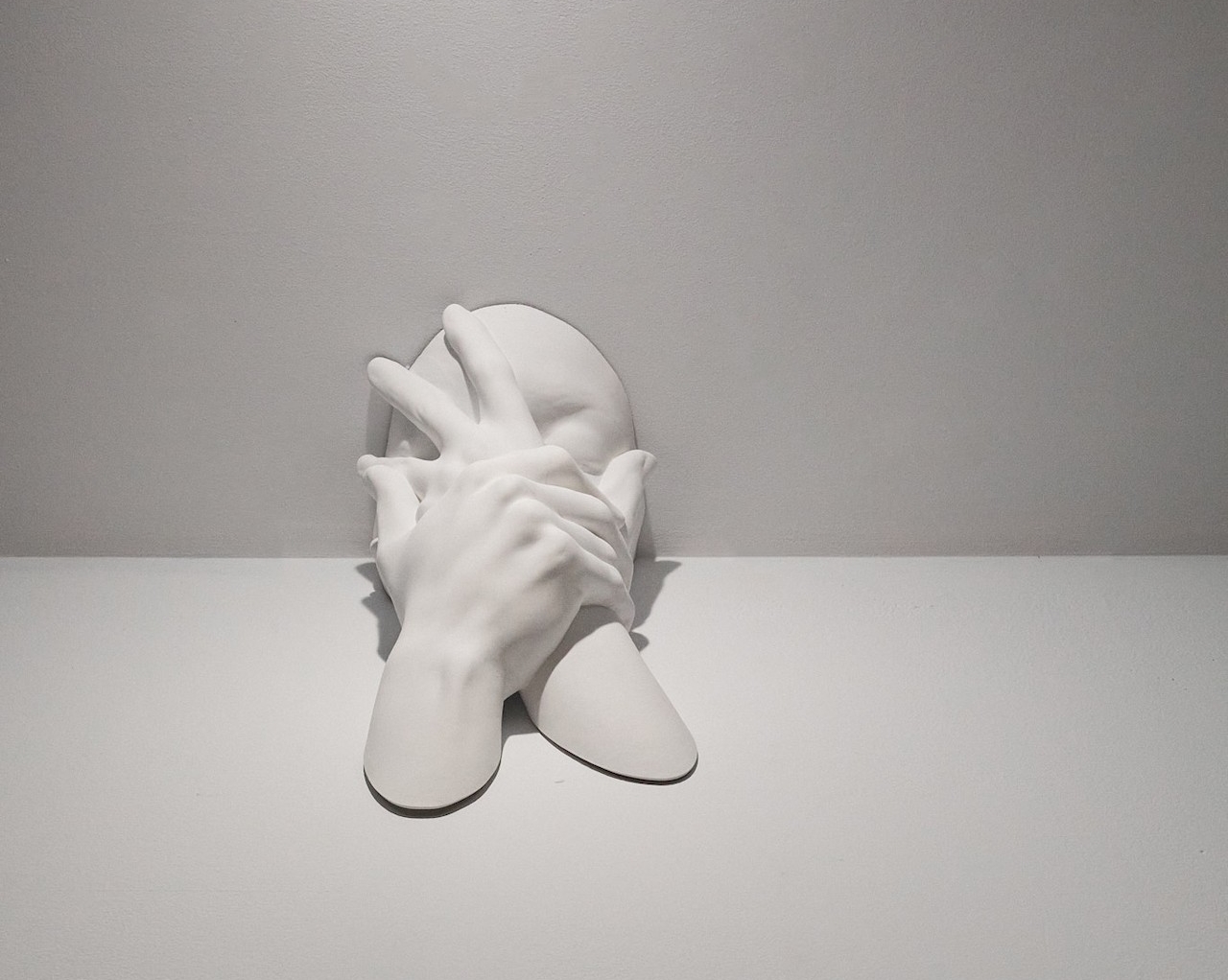 Sculpture of face covered by hands, Po B. K. Lomami