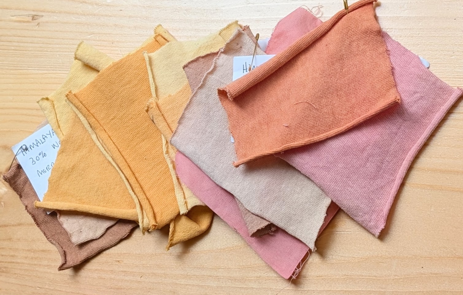 an image of several swatches of natural dyes, spanning rich yellows, oranges, and nearly pink colours.