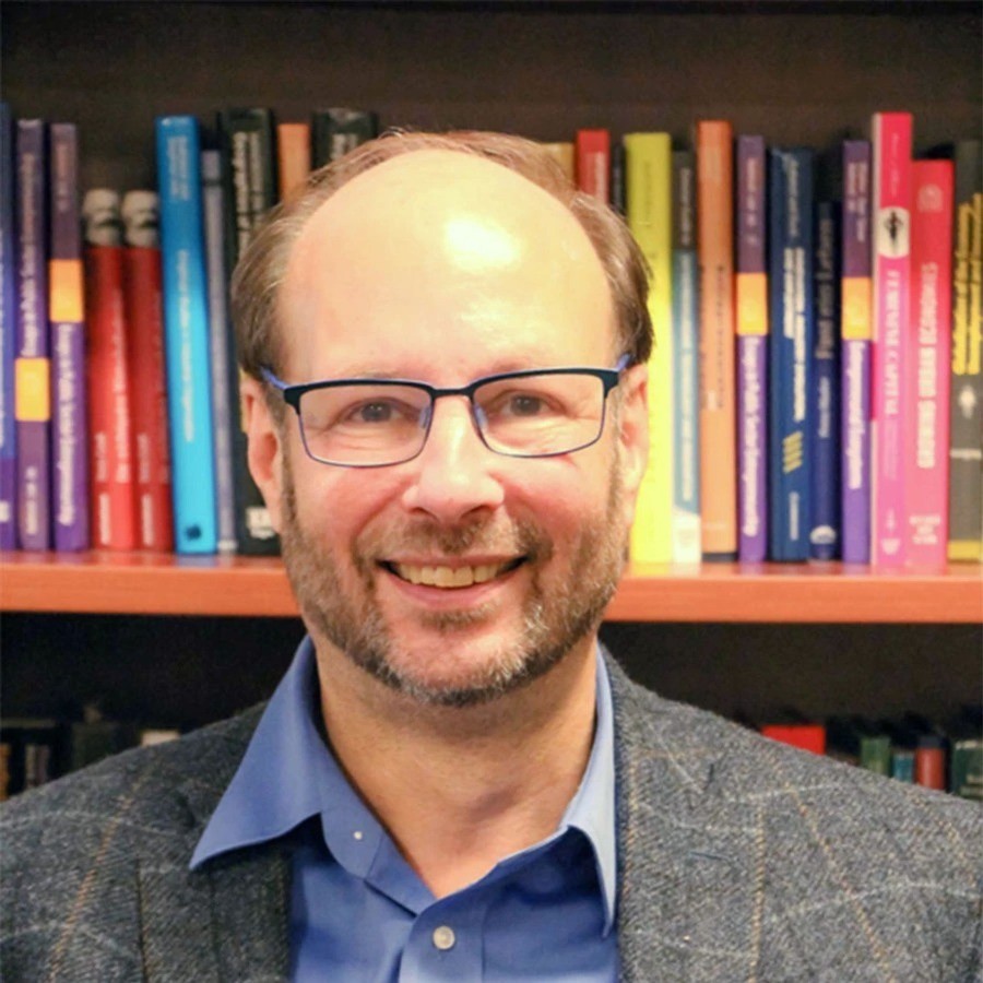 David B. Audretsch smiling with black glasses and bookshelf in background