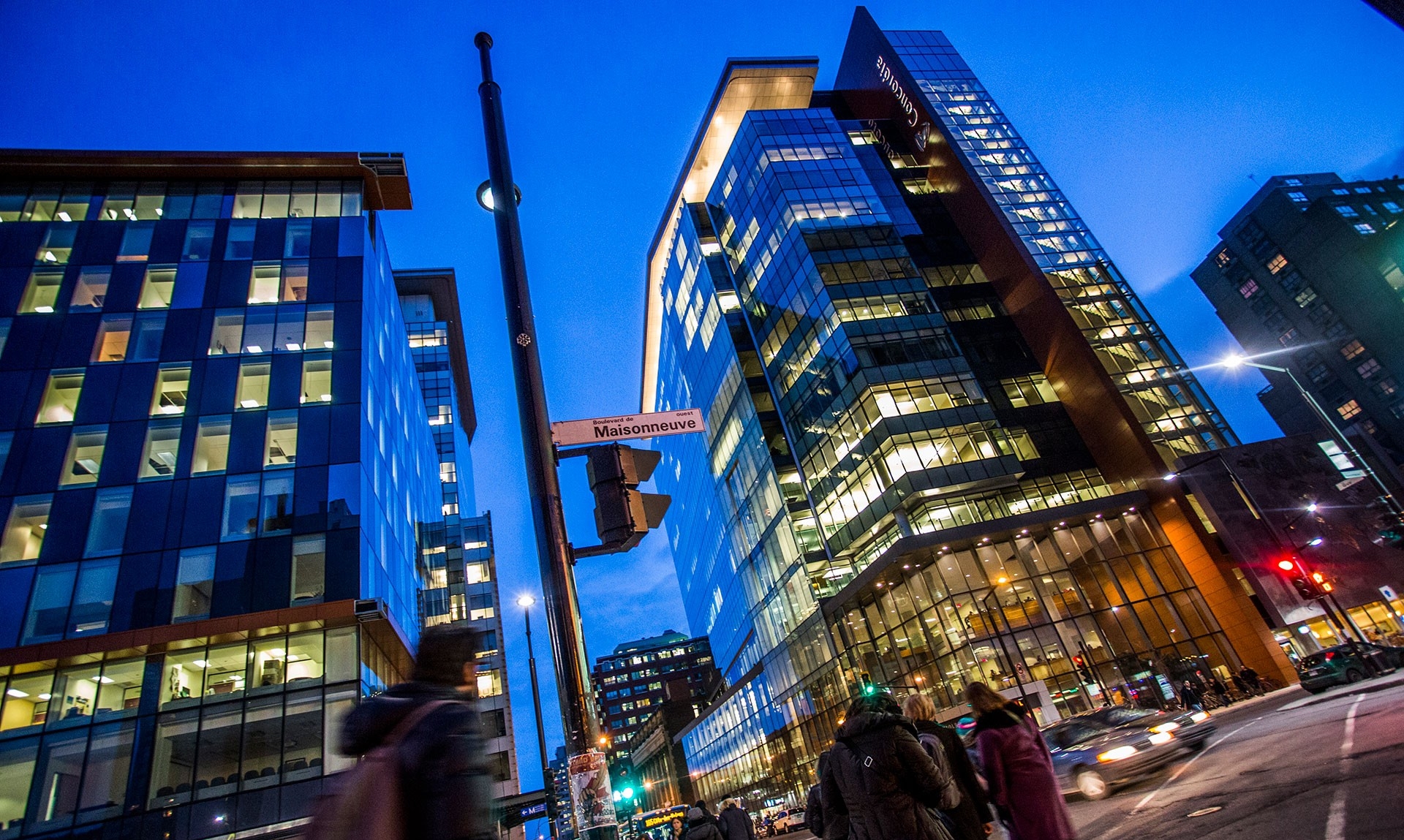 Concordia downtown campus showing tall buildings lit at night with pedestrians on the street