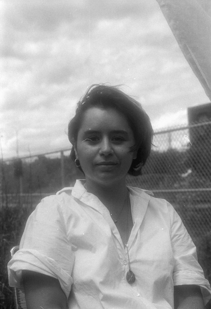 Young woman with short(ish) dark hair and a white shirt.