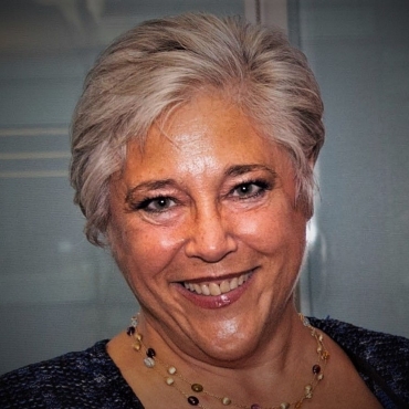 Headshot of smiling woman with short hair wearing delicate beaded necklace
