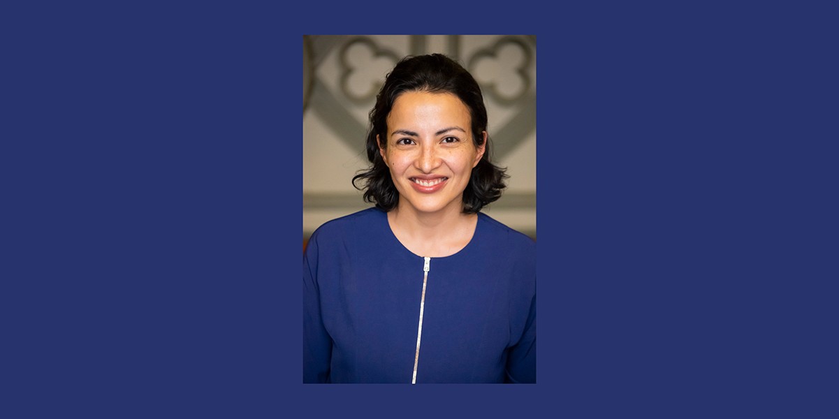 Smiling woman with short black hair wearing zip-up blue sweater