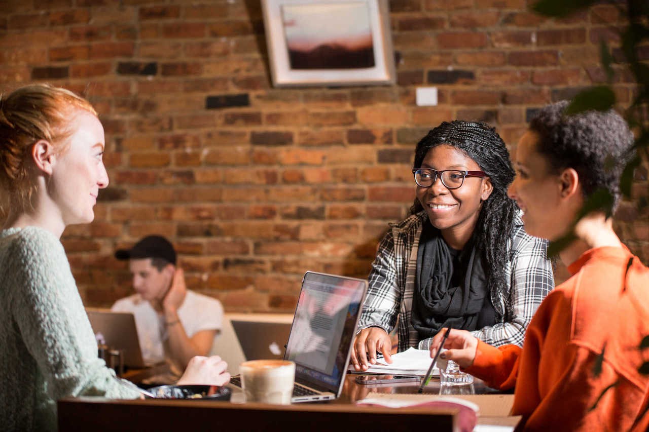 Three women working and chatting inside a coffee shop