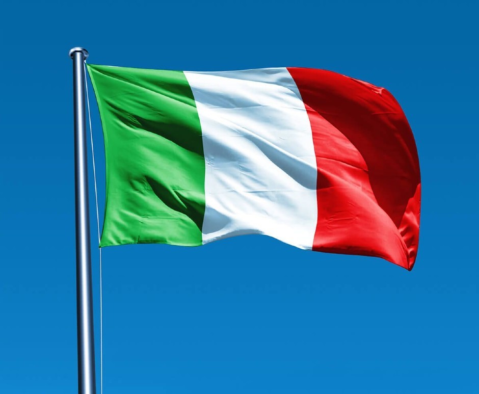 An Italian flag on a flag pole set with a blue sky background
