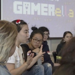 Group of young women in front of projector screen that reads GAMERella