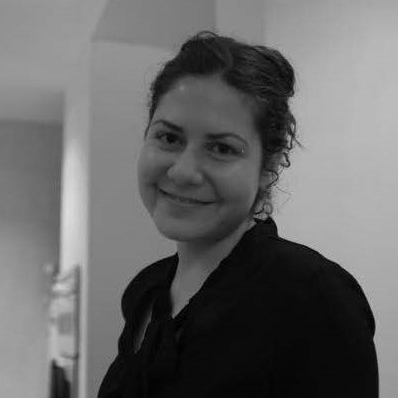 Black-and-white photo of woman with dark hair pulled back in dark shirt smiling.