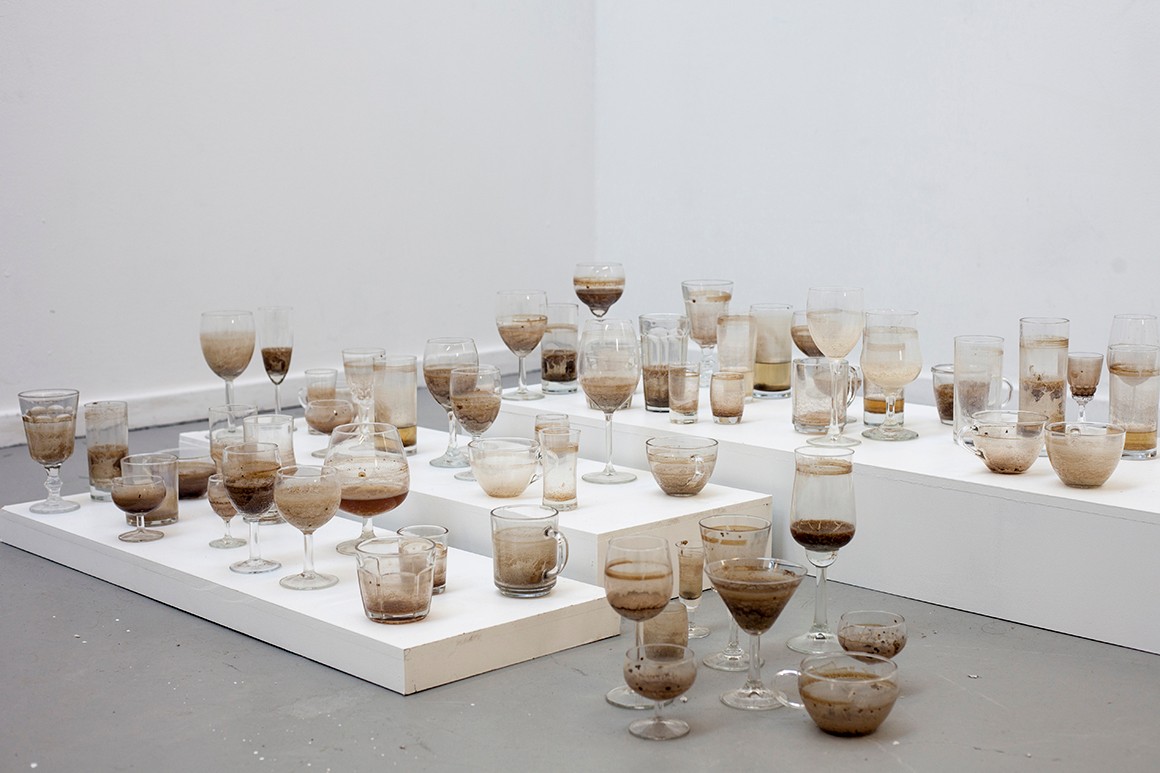 A collection of 100+ regular glasses, stemmed glasses and small bowls containing various amounts of brown liquid
