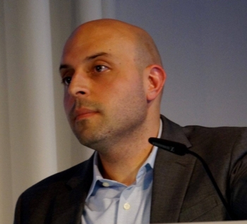 Side profile of man wearing black blazer and light-blue collared shirt