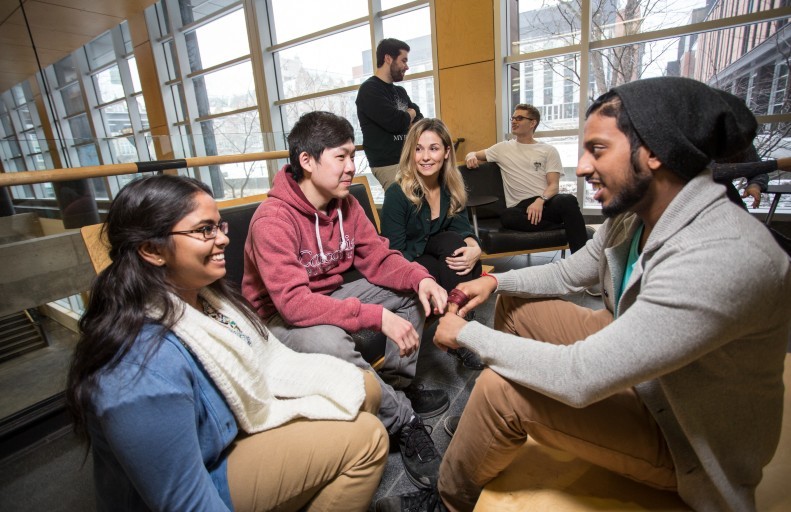 A group of smiling students sit together in the Richard J. Renaud Science Complex on the Loyola Campus.