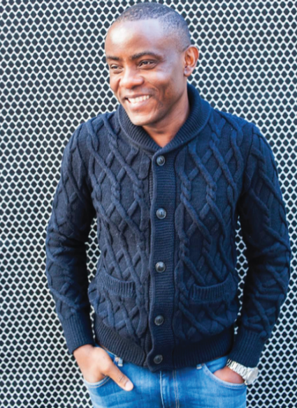 Smiling Black man wearing button-up cardigan with blue jeans