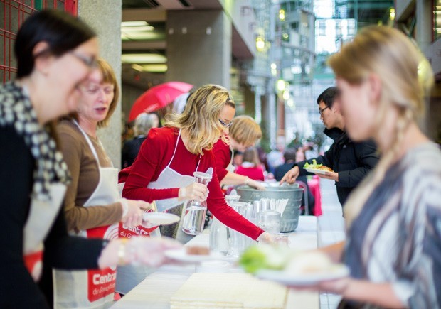 People wearing aprons serving food behind a table