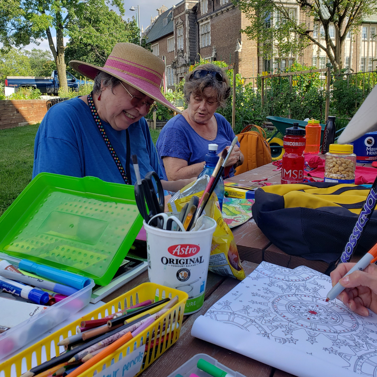 community sitting around a picnic table at a garden making art