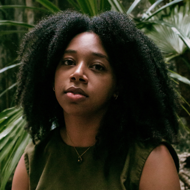 portrait of woman with tropical plant foliage in the background