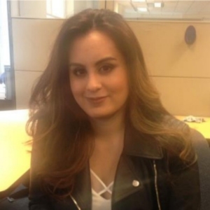 A woman with long brown hair wears a leather jacket