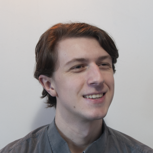 A man with short brown hair wears a collared shirt