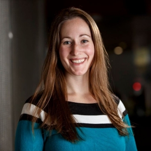 A woman with long brown hair wears a striped sweater