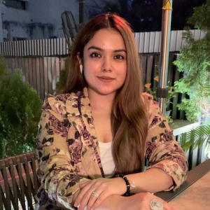 A woman with a floral print blazer sits at an outdoor table