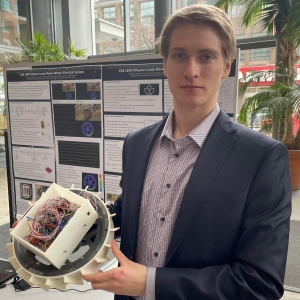 A man with a checkered shirt and blazer presents his research during a poster event