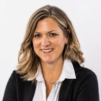 A smiling woman with blonde hair, wearing a white blouse and black blazer. 
