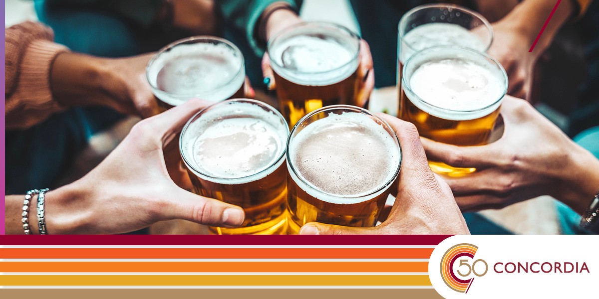 A photo of several hands clinking beer pints together for a toast.