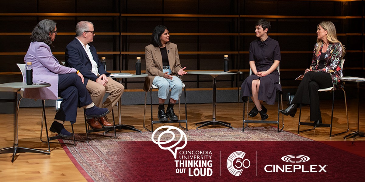 5 professors sitting on stools speak to each other on a stage