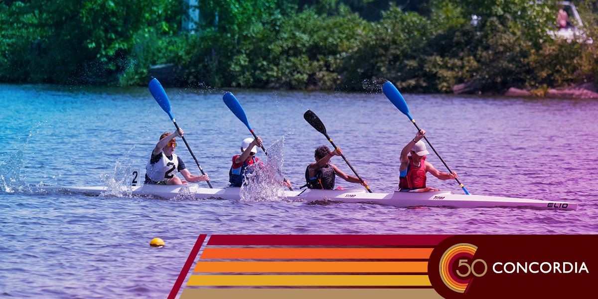 Four people are in a kayak on a still lake.
