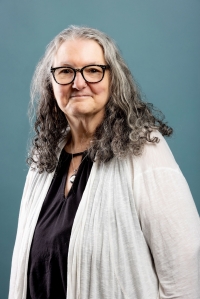 Smiling woman with shoulder length grey hair looking straight ahead
