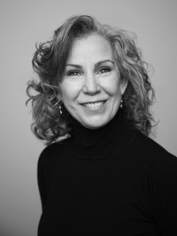 Black and white photo of a smiling woman with grey hair looking straight ahead