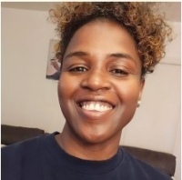 Smiling person with short curly hair looking into the camera.