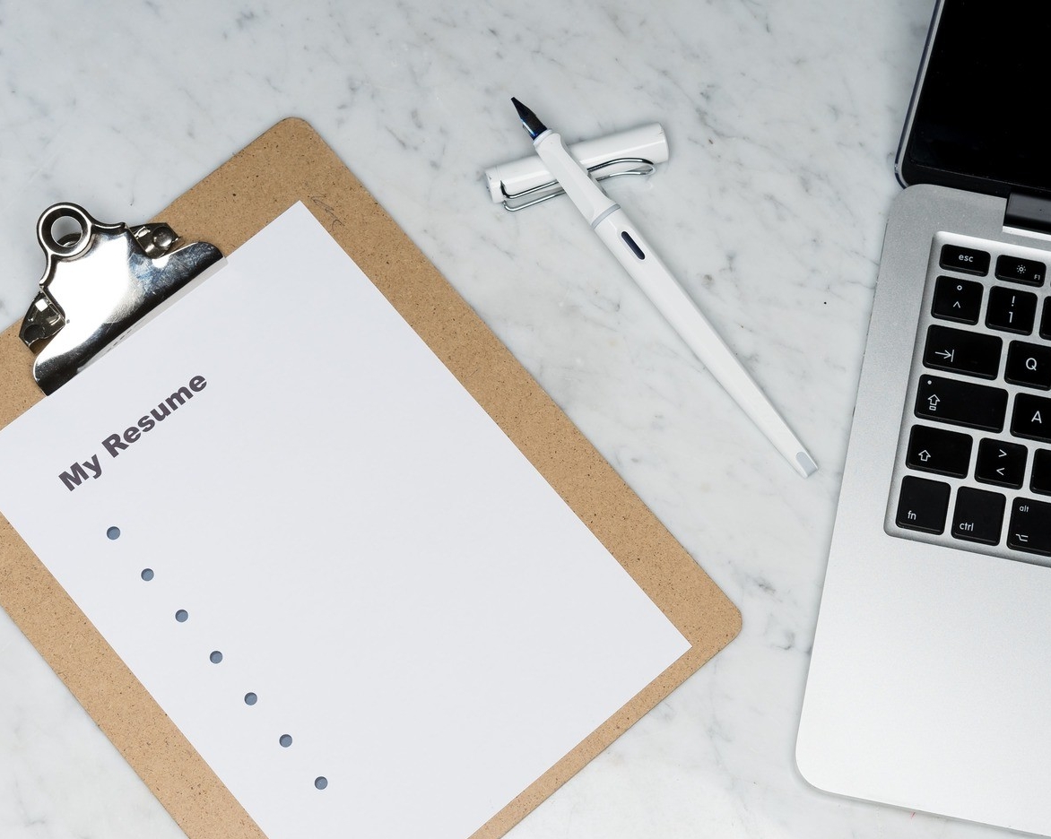 clipboard next to laptop and pen