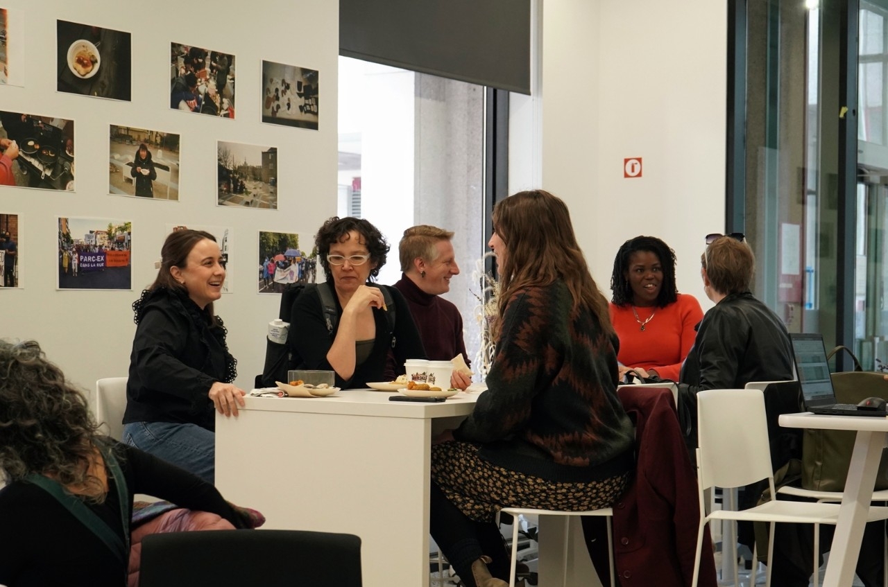 people seated aound a table eating and talking in an open space