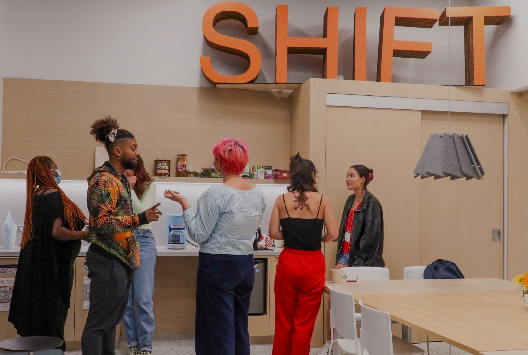 6 student interns chatting in front of the SHIFT Centre's coffee area.