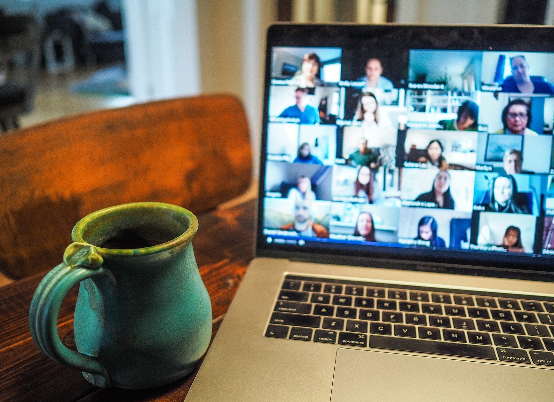 turquoise mug set on wooden table next to a laptop showing a zoom meeting session