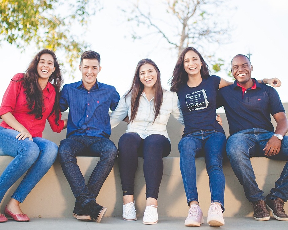 a group of students sitting on a bench outside smiling