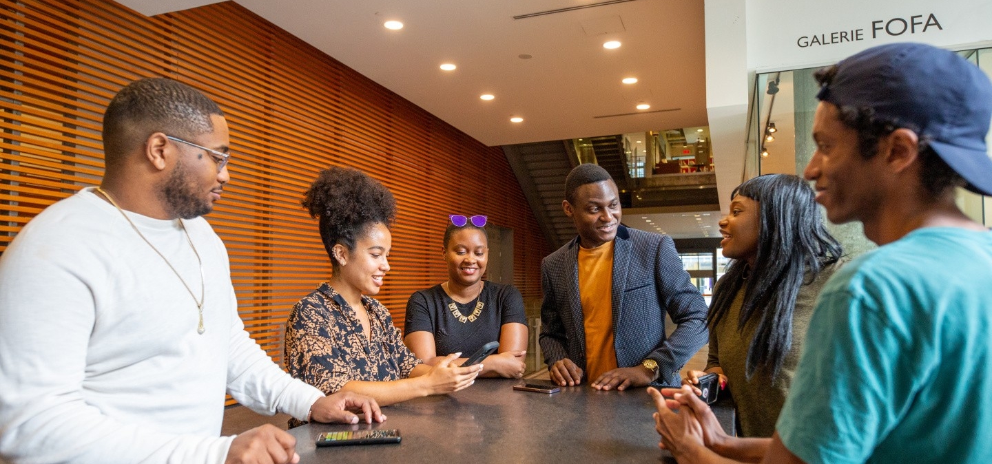 Six Concordia students sit at a big table in the EV atrium and chat