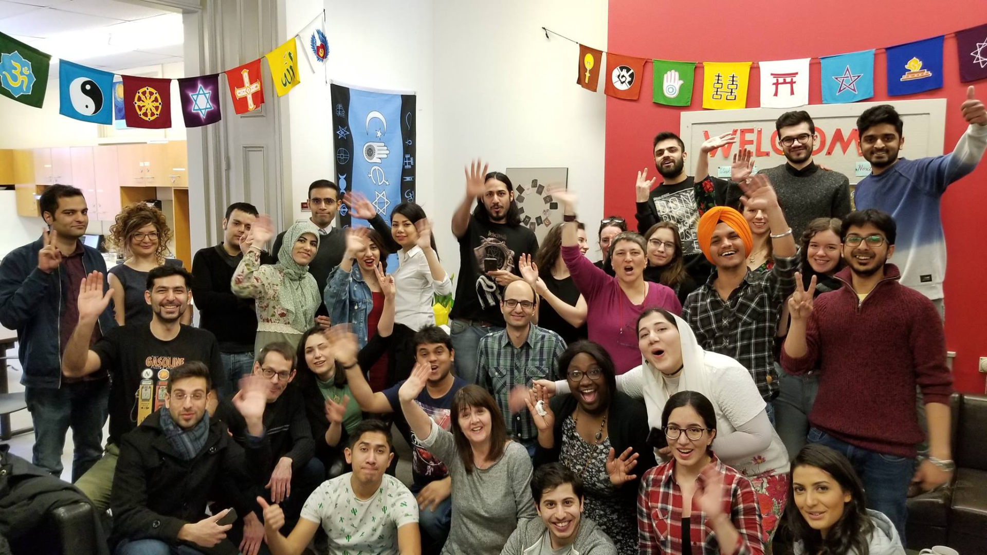 A group of smiling students posing for a picture and waving