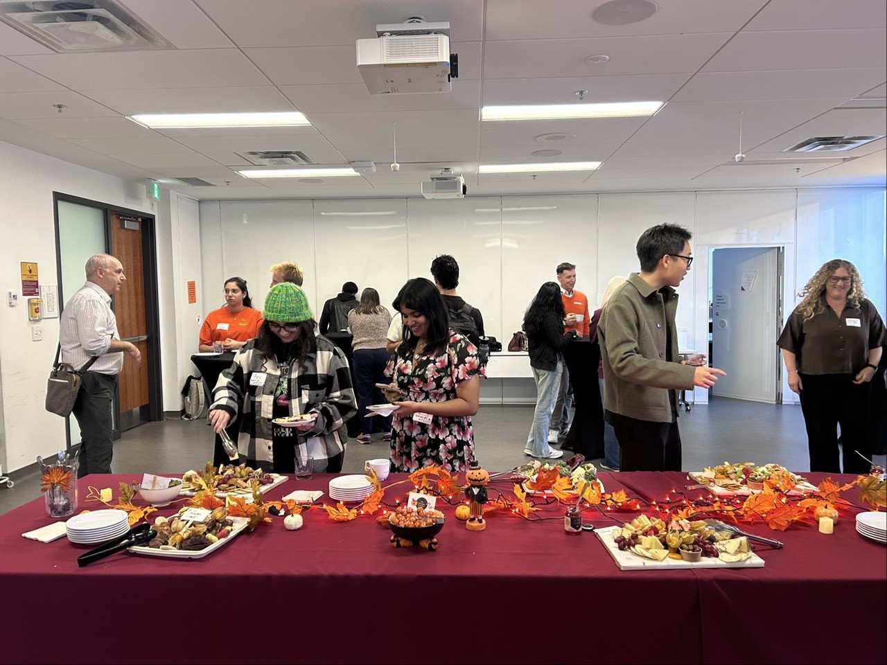 students networking at an event with food and fall themed decorations