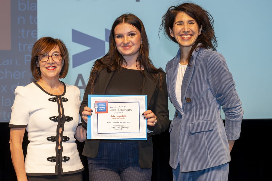 A student holding an award and two women