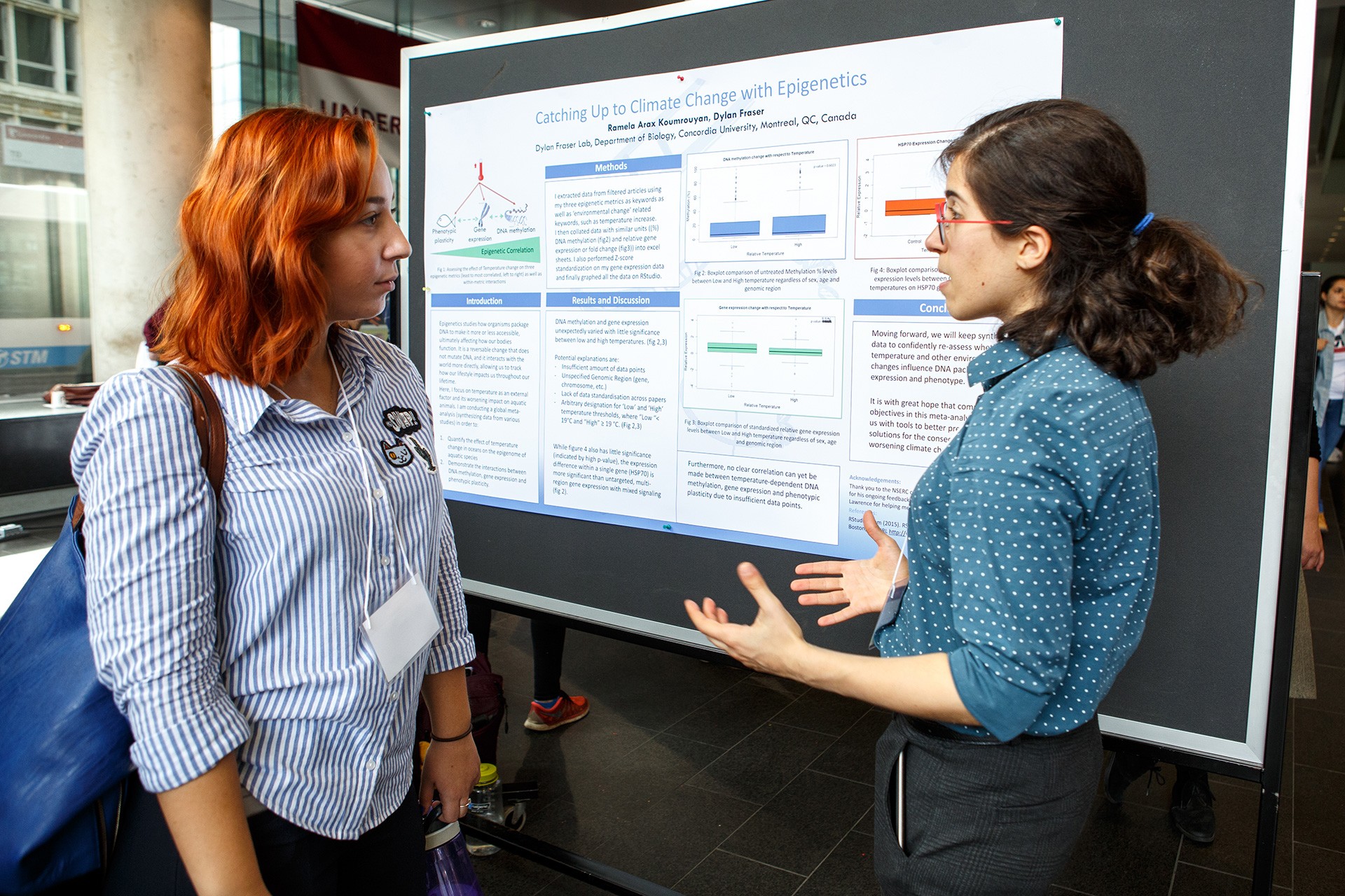 Female student explaining a research poster to another female student
