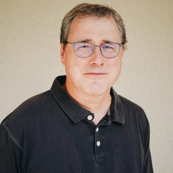 Headshot of man wearing black polo
