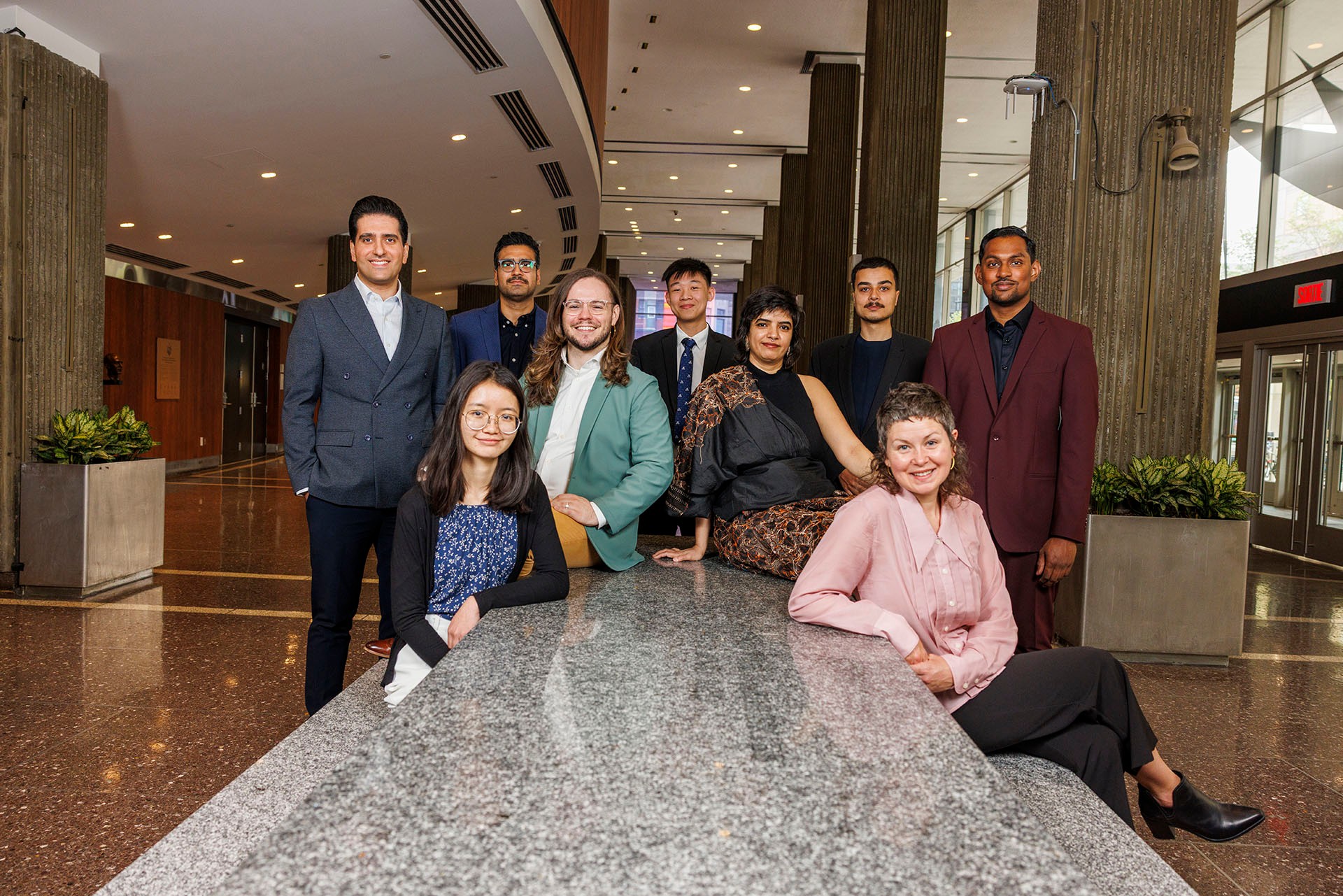 Nine public scholars gathered at the edge of a table facing the camera