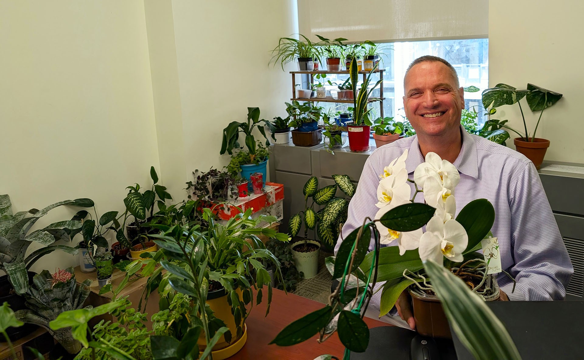 Man sitting down surrounded by plants in an office space