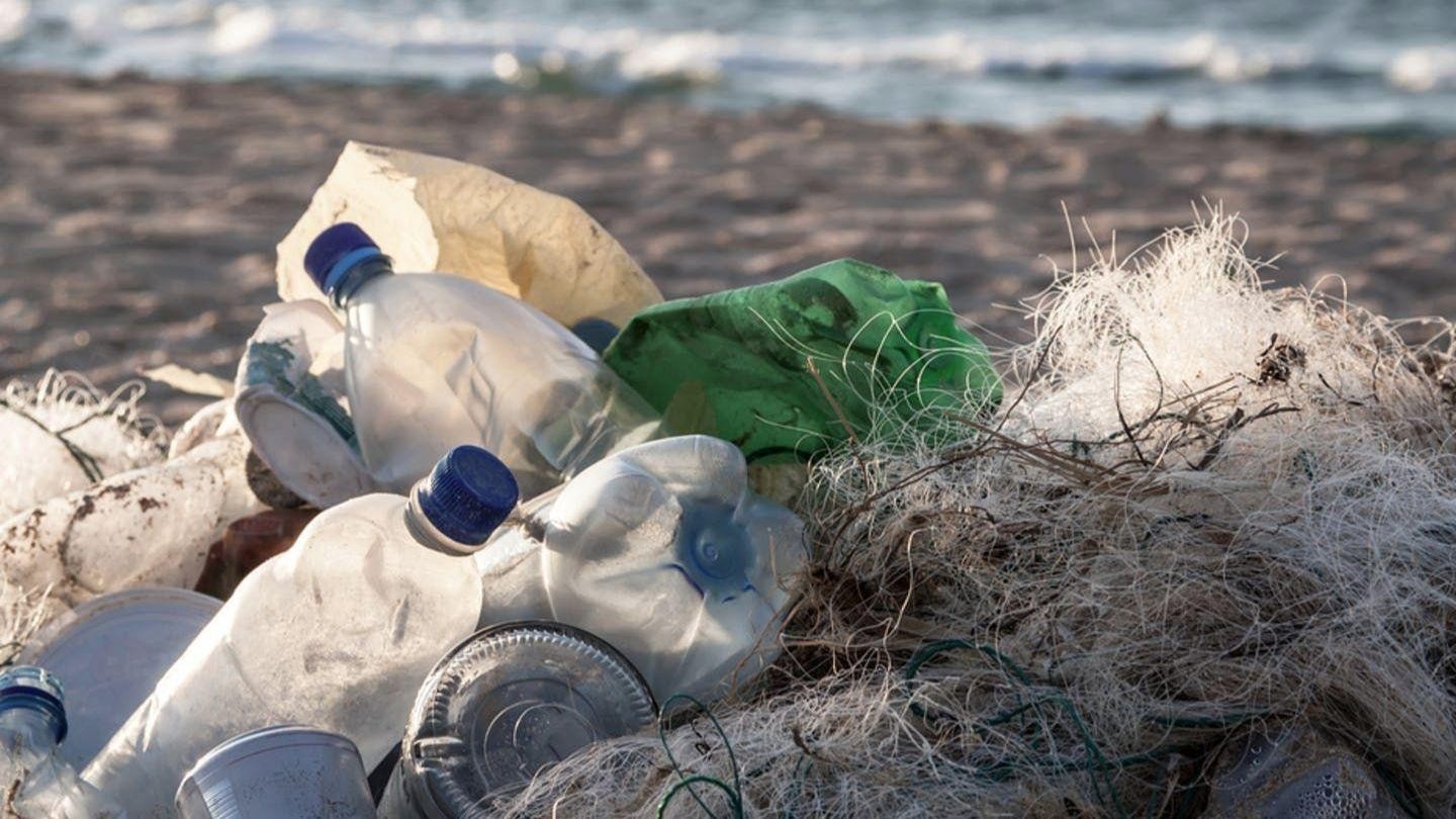 Plastic water bottles and other plastic debris sit tangled up on a beach