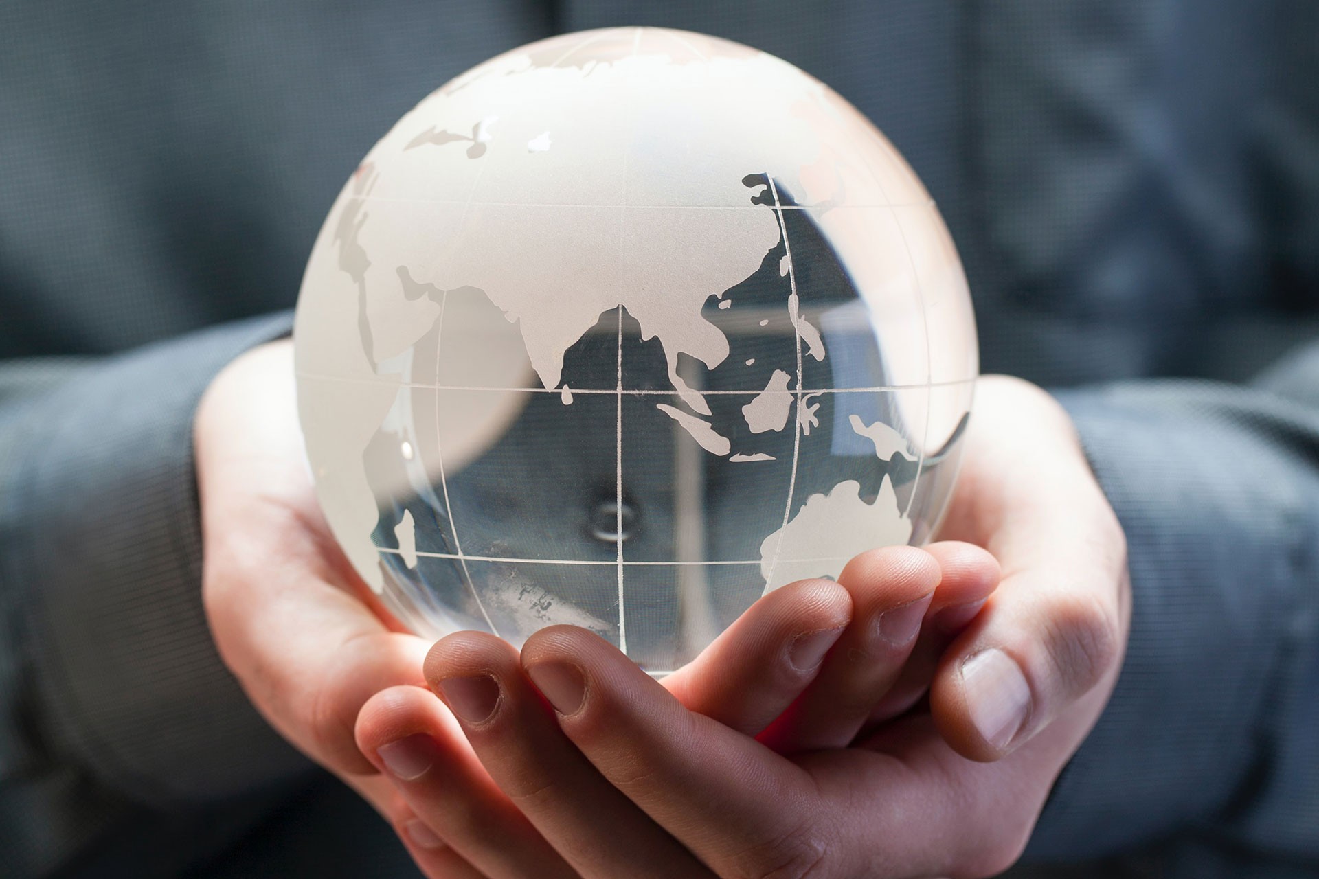 Hands hold a crystal globe of the planet earth
