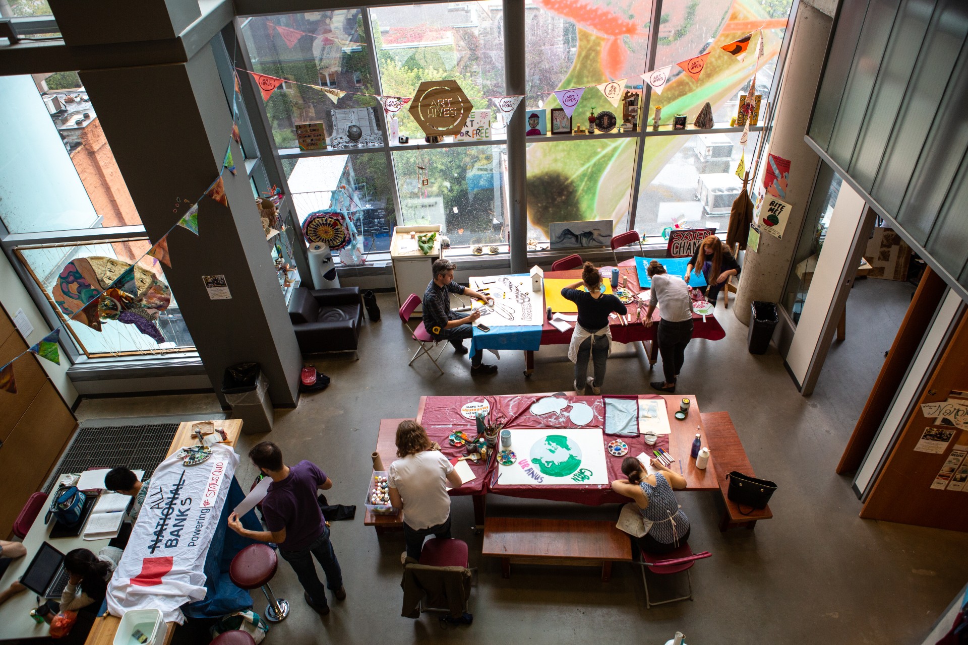 Photographed from the balcony above, Concordians sit and stand at tables in the EV building painting signs for the climate march in 2019.