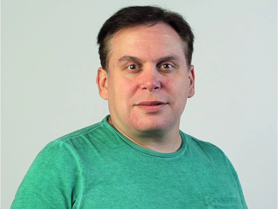 Middle-aged caucasian man against white background. Short-cropped brown hair and seafoam green tee-shirt.