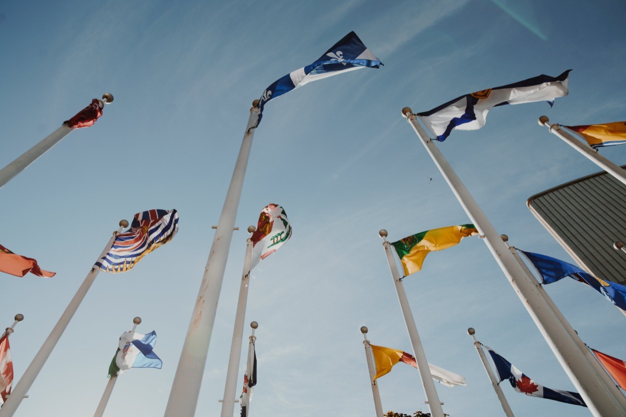 Provincial flags from below, blowing in the wind against a blue sky.