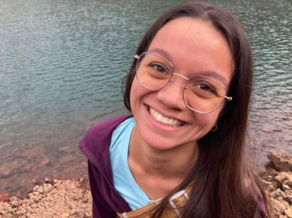 Kelly Burchell-Reyes smiling broadly with stone beach and water in the background