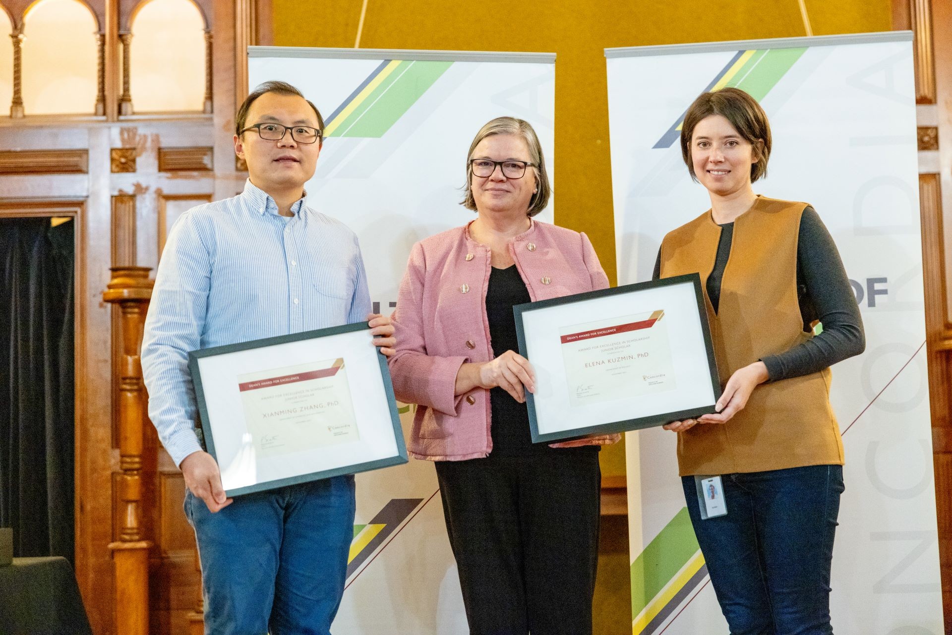 Two researchers, a man and a woman, standing on each side of Dean Sicotte, holding their framed award